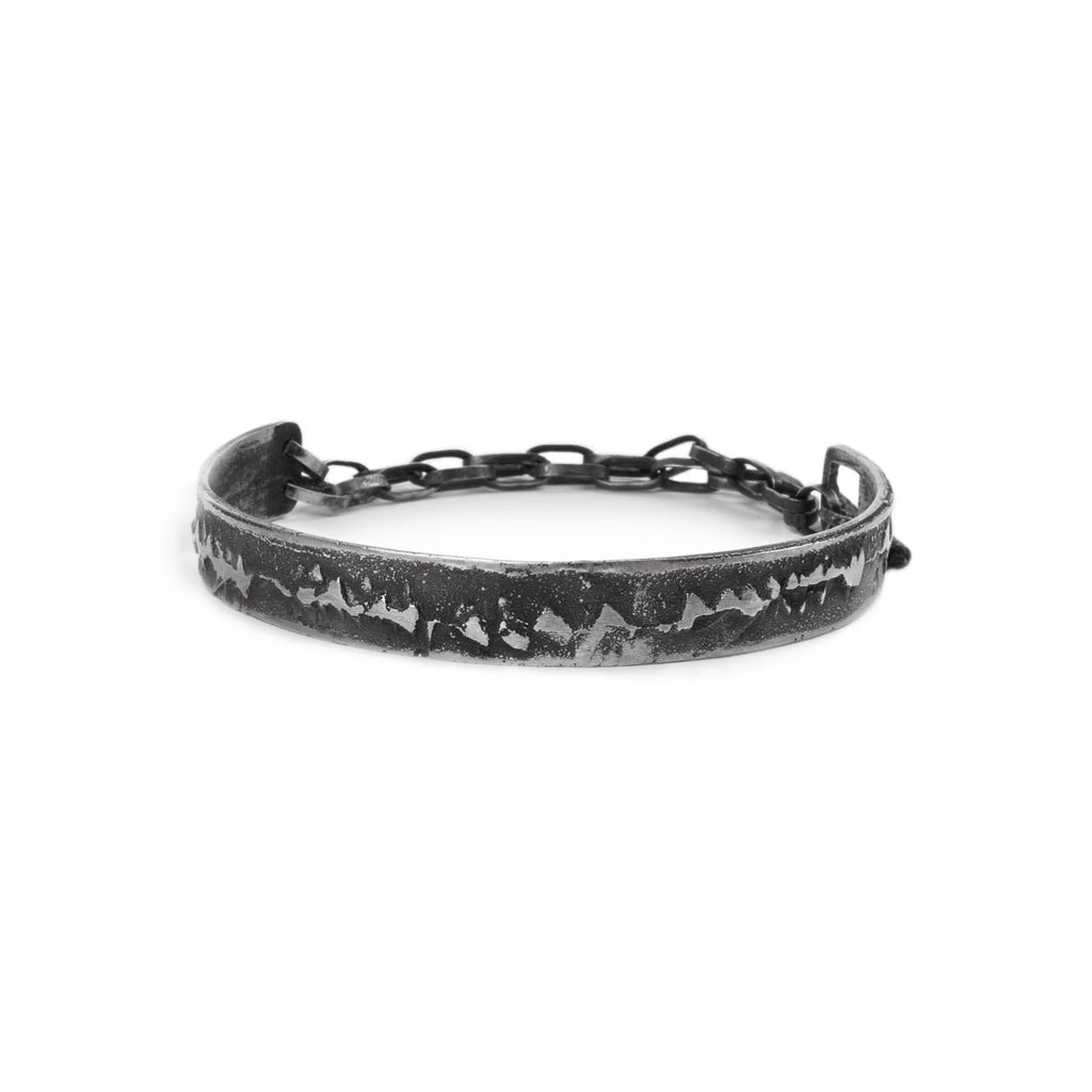 Silver cuff bracelet with texture and chain on a white background made in Berlin