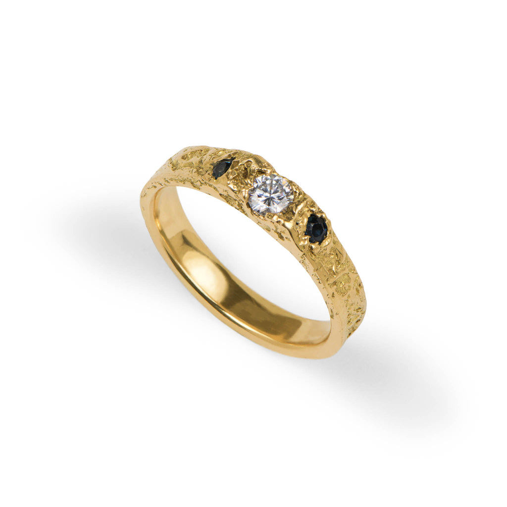 Gold ring with a diamond and black stones on a white background