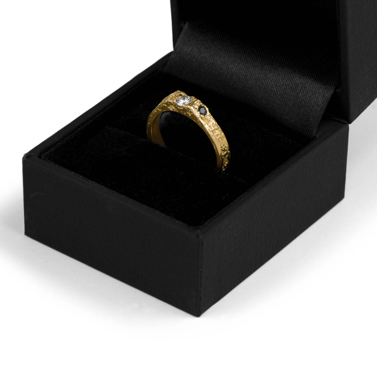Gold ring with a diamond in a dark jewelry box on a white background
