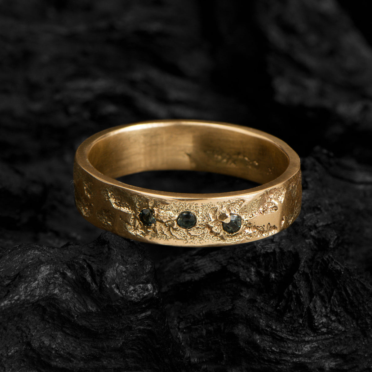 Organic gold band with three brilliant cut tourmalines on a dark background