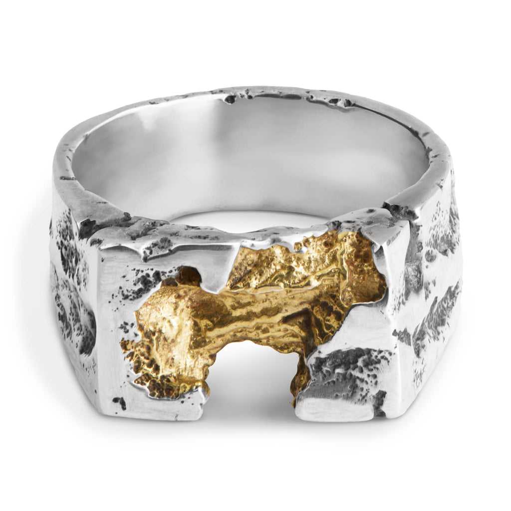 Sculptural sterling silver signet ring with gold plated center laying on a white background.