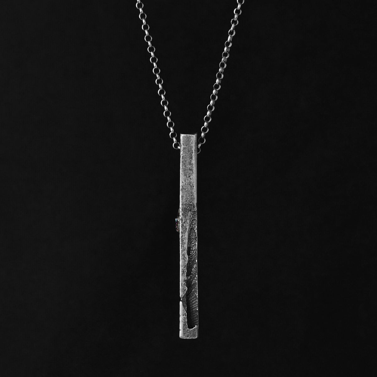 Textured silver monolith pendant gainst a blöack background