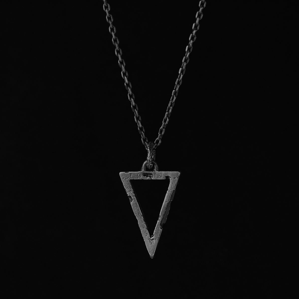 Silver triangle pendant with an organic textured finish suspended from a sterling silver chain handcrafted in Berlin.
